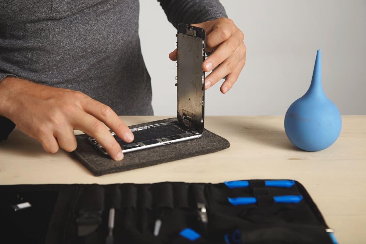 A man removing a broken screen from a smartphone during a repair