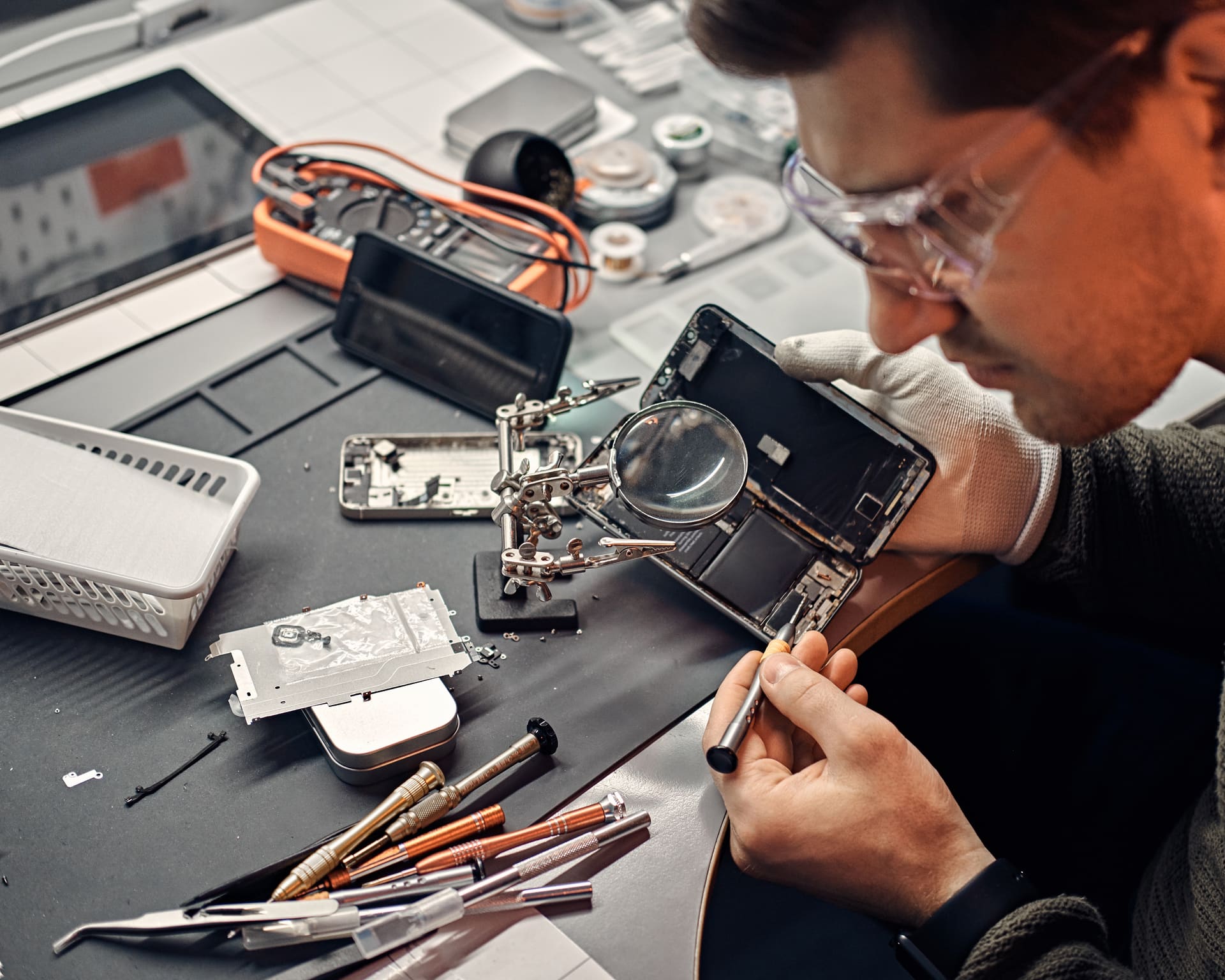 A repair technician working on a phone at the bench