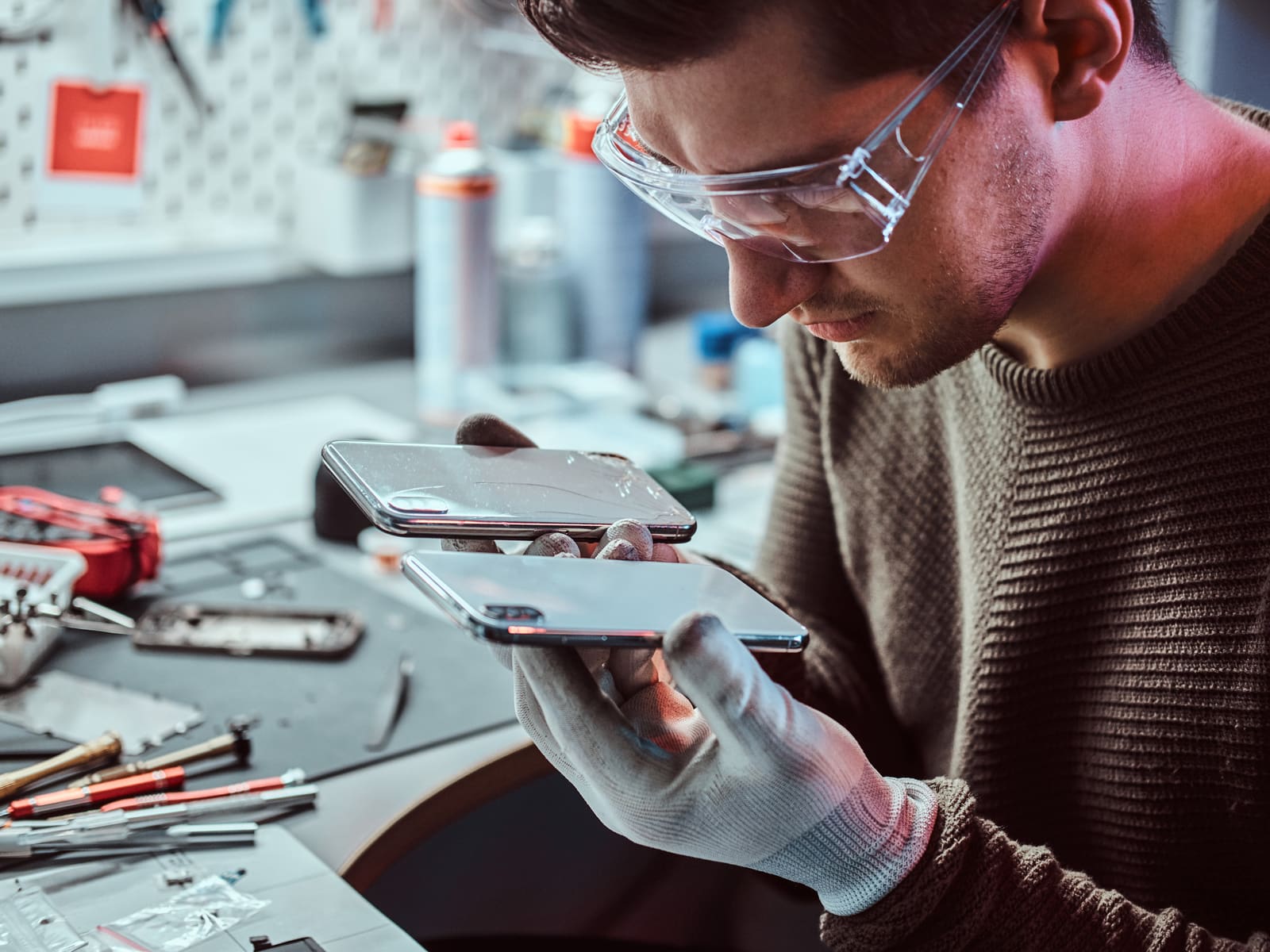 A technician inspecting a smartphone at a repair bench